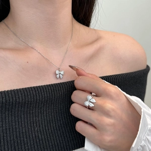 Close-up of a silver bow necklace and matching ring with zircon inlay on model