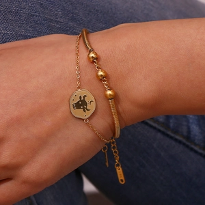 Close-up of Taurus zodiac charm and golden double-layer chain bracelet worn on wrist