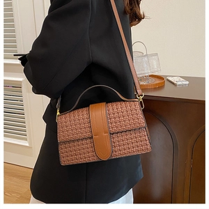 Close-up of brown woven texture handbag with golden hardware and leather strap detail