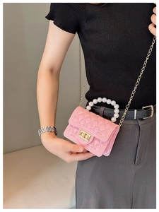 Pink quilted crossbody bag detail with pearl handle and golden chain strap on model