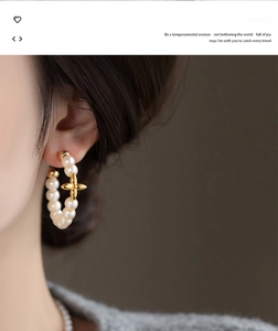 Close-up of elegant gold-plated C-shaped earrings with pearls and star charm on a model