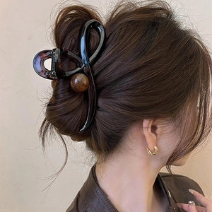 Crossed large hair claw clip with tortoiseshell ball accents for elegant hair styling