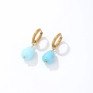 Detail of gold waterdrop earrings with light blue natural stones on white background