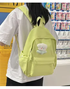 Pale green nylon backpack on model featuring a cute white teddy bear plush charm