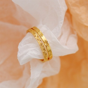 Detail view of gold-plated rings with intricate starburst engravings on light paper