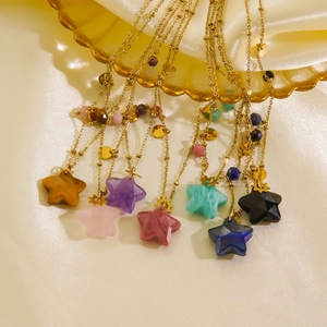 Star pendant necklaces with natural stones on gold chain displayed on elegant silk fabric