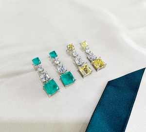Detailed view of long dangling earrings with Asscher cut yellow and green crystals