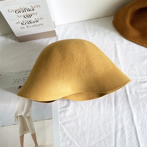 Texture détaillée du chapeau cloche en laine jaune sur tissu blanc avec livres