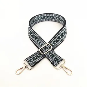 Close-up of geometric V-pattern woven bag strap with golden metal lobster clasps