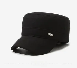 Detail of a black winter flat top cap with a metal fashion logo and warm wool texture