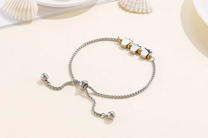 Detail of adjustable tulip charm bracelet in silver with golden beads and a pull-string clasp