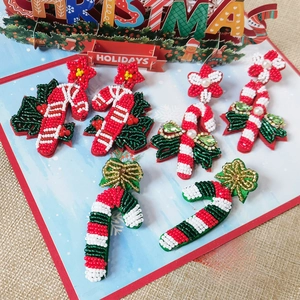 Detail shot of handmade beaded Christmas earrings with bow and festive ornament designs