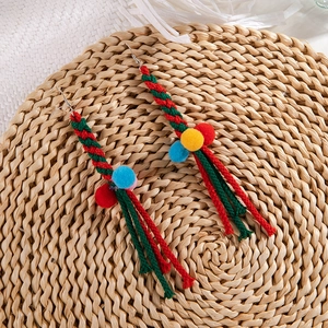 Detail view of handmade Christmas earrings with colorful pompoms on a natural woven mat