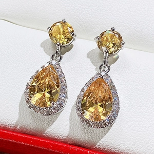 Macro view of pear-cut yellow zircon earrings with silver metal and white pave setting