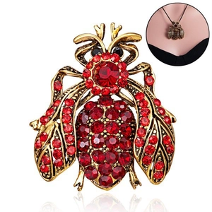 Macro detail of bee brooch featuring vintage gold finish and red rhinestone embellishments