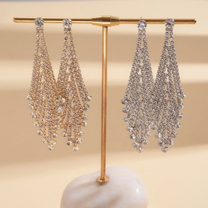 Detailed view of long rhinestone tassel earrings in gold and silver on a display stand