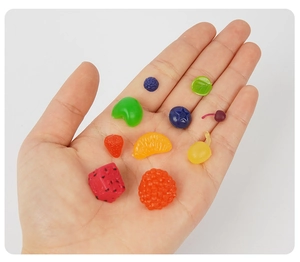 Vista macro de dijes de frutas en miniatura de resina surtidas para manualidades DIY