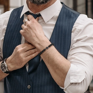 Men's natural black stone beaded bracelet with woven strap shown on a model