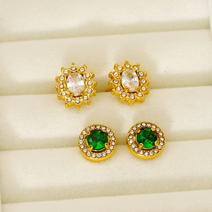 Elegant gold flower and round stud earrings with zircons in a beige jewelry box