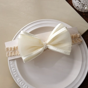 Bandeau bébé en dentelle beige avec grand nœud en satin et détails de perles