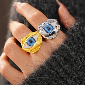 Detailed close-up of gold and silver irregular resin eye rings on a grey knit background