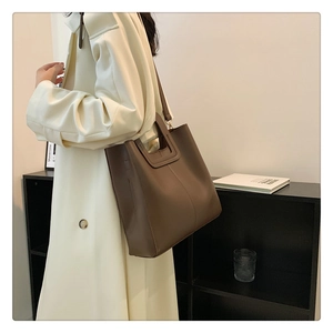 Brown leather bucket bag styled on shoulder, showing medium-large capacity and elegant fit