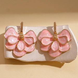 Detailed view of pink enamel flower earrings on a minimalist stone display stand