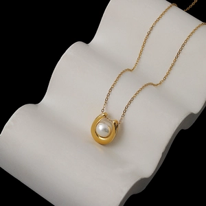 French style 18K gold U-shaped pendant necklace with white pearl on white pedestal