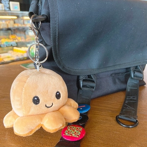 Creative reversible orange plush octopus keychain hanging on a black backpack strap
