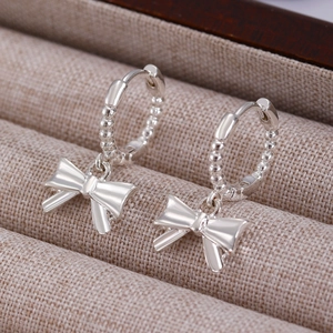 Vue macro de boucles d'oreilles nœud argentées texturées sur un support à bijoux chic