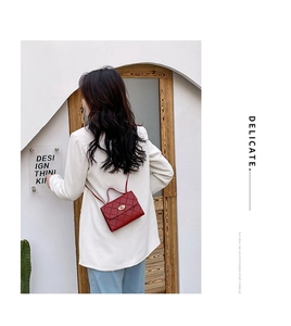 Model wearing a red quilted crossbody handbag with a stylish chain strap on a shoulder