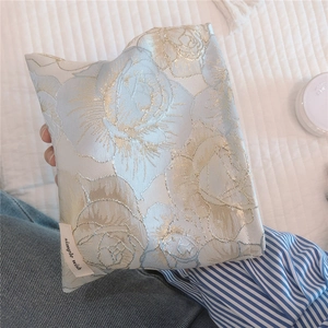 Macro shot of elegant rose jacquard fabric makeup bag with golden floral embroidery detail