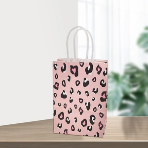 Sac cadeau en papier kraft rose avec imprimé léopard et poignées blanches sur bois