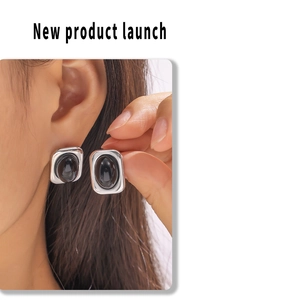 Close-up of model wearing silver earrings featuring a large oval black gemstone