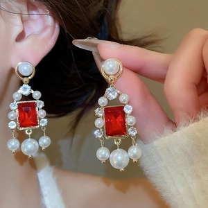 Détails macro de boucles d'oreilles vintage dorées avec pierres rouges et perles