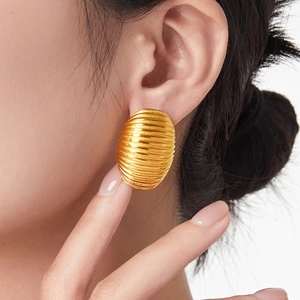 Elegant gold ribbed oval hoop earrings with textured finish shown on a female model