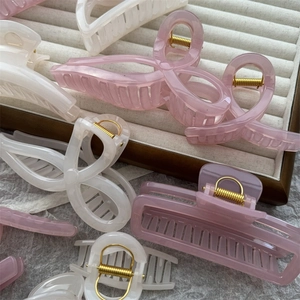Close-up of pink and white translucent resin hair claw clips on a beige ribbed tray
