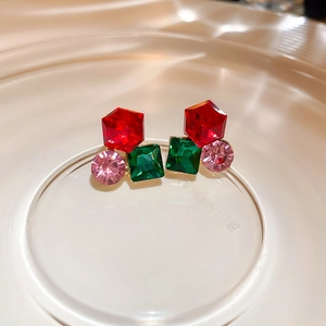 Macro view of geometric silver needle earrings featuring colorful inlaid crystals