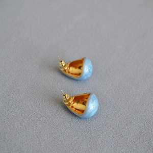Macro detail of blue marble enamel teardrop earrings with polished gold inner finish