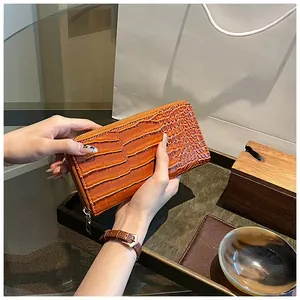 Detail of an orange crocodile pattern wallet showing the sleek texture and gold zipper