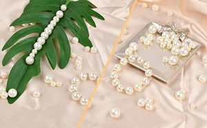 Detailed view of cream white DIY pearl beads on green leaf and elegant silver tray