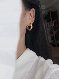 Macro side view of chunky gold hoop earrings with a high-polished mirror finish