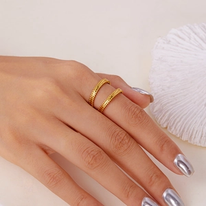 Macro detail of gold-plated geometric stainless steel rings with granular texture on model