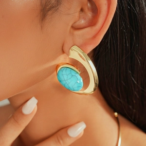 Close-up of a model wearing a gold twisted C-shape earring with a marbled blue oval resin stone
