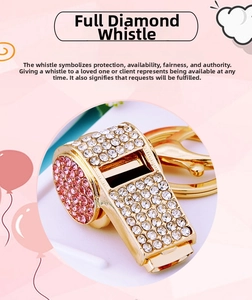 Detailed macro view of a gold-plated metal whistle keychain with pink and white rhinestones