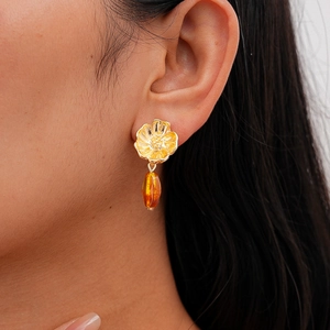 Detailed view of vintage gold flower earring with a resin amber teardrop pendant