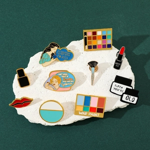 Macro shot of creative makeup-themed enamel pins with slogans on white textured stone