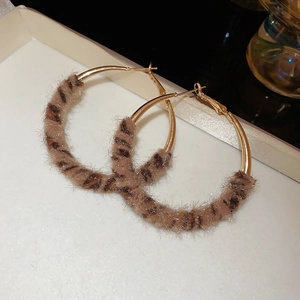 Gros plan de boucles d'oreilles créoles dorées avec texture peluche léopard
