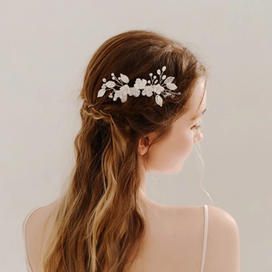 Elegant bridal hair comb with white ceramic flowers and pearls on a model's brown hair