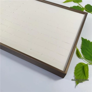 Macro view of 100-slot jewelry display tray with cream velvet lining and dark brown frame